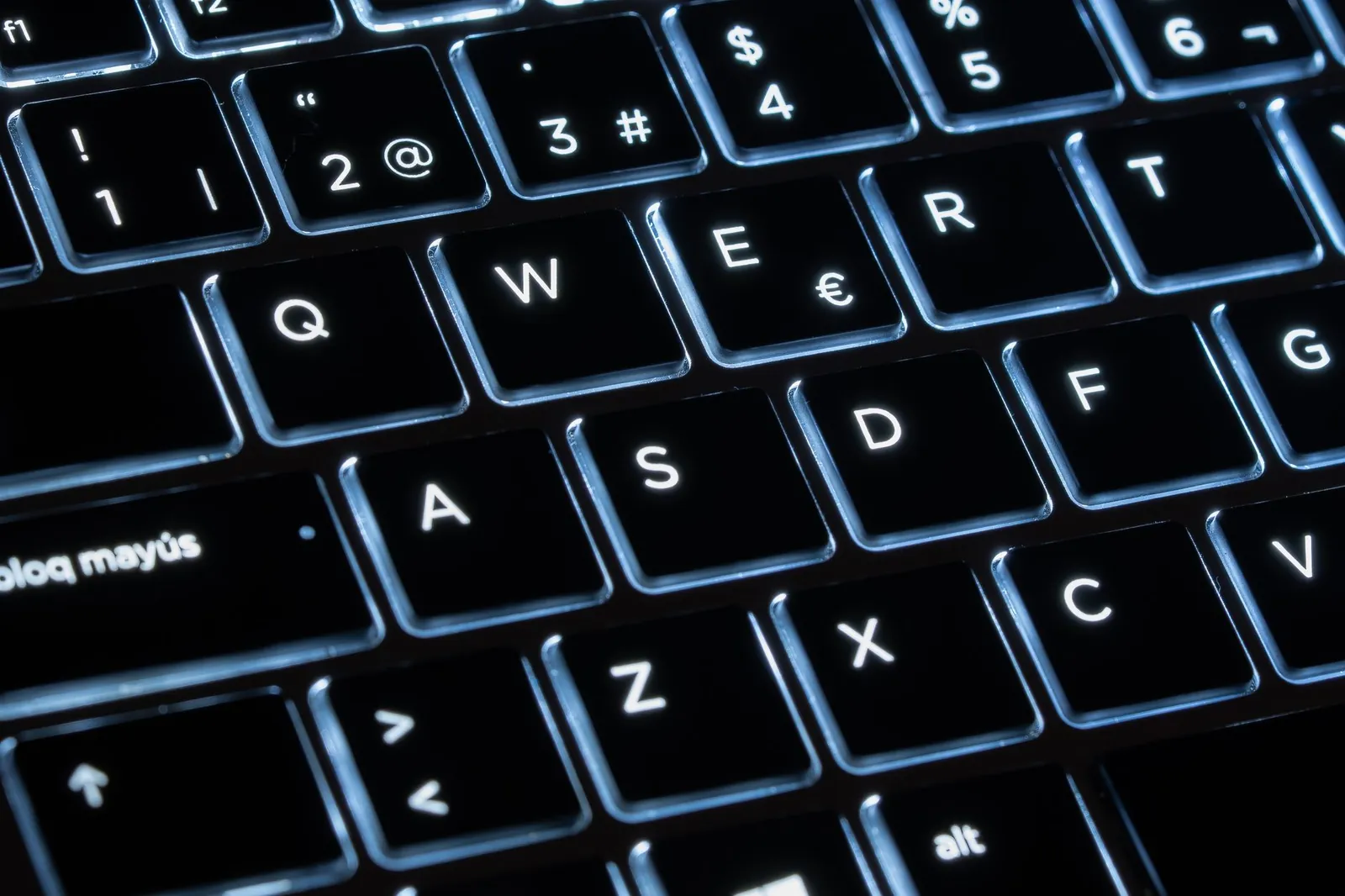 Close-up of a dark mechanical keyboard with cyan backlight